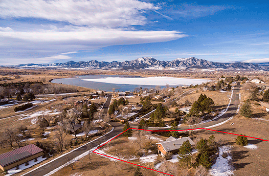 An aerial photo of a neighborhood with a lake in the background with snow, and a snow-topped mountain even further back.An aerial photo of